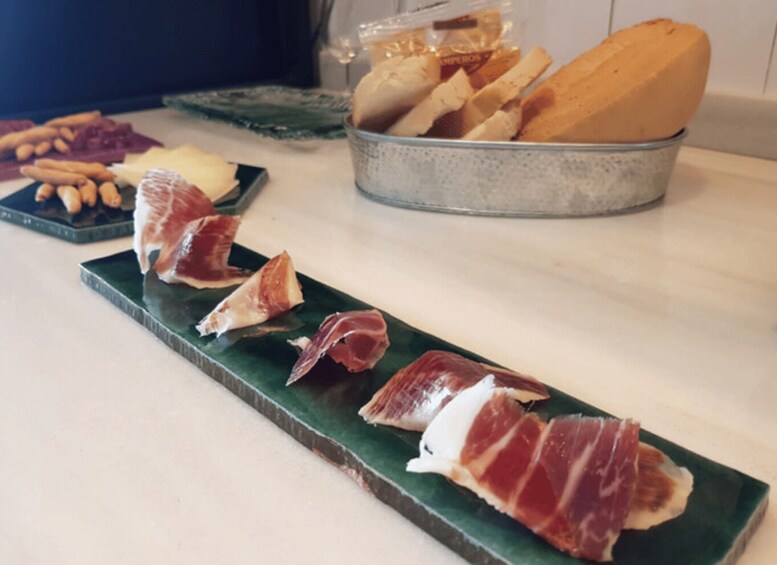 Una tabla de fiambres con jamón serrano, queso y pan. 4