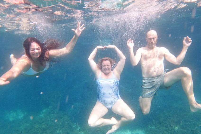 Three people swimming underwater. 3