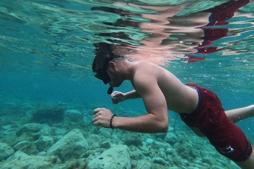A person swimming underwater with a snorkel, surrounded by underwater rocks and coral. 4