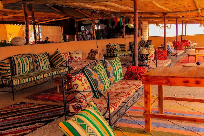 A covered outdoor seating area with colorful patterned cushions and a wooden table. 4