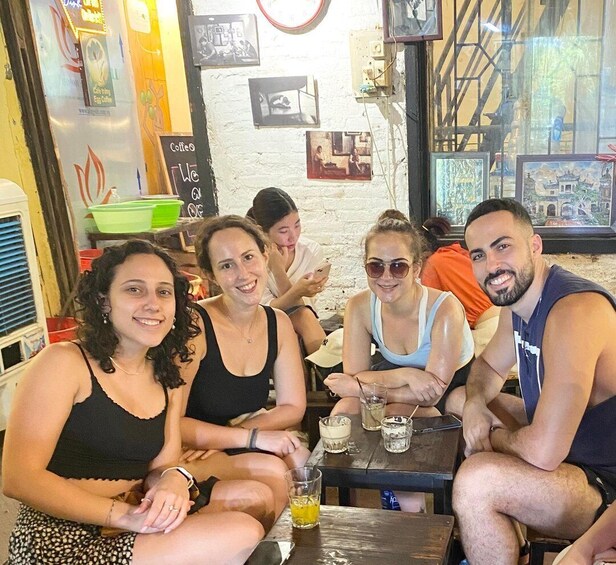 Un grupo de personas sentadas en una mesa en un café con decoración rústica, que incluye un reloj y cuadros en la pared. 1