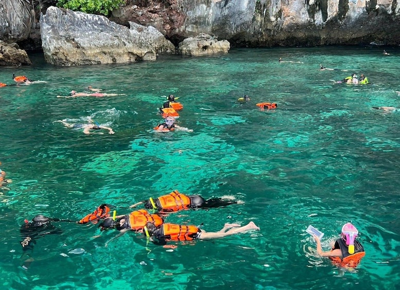 Des personnes font de la plongée avec tuba dans une eau turquoise et limpide, avec des falaises rocheuses en arrière-plan. 5