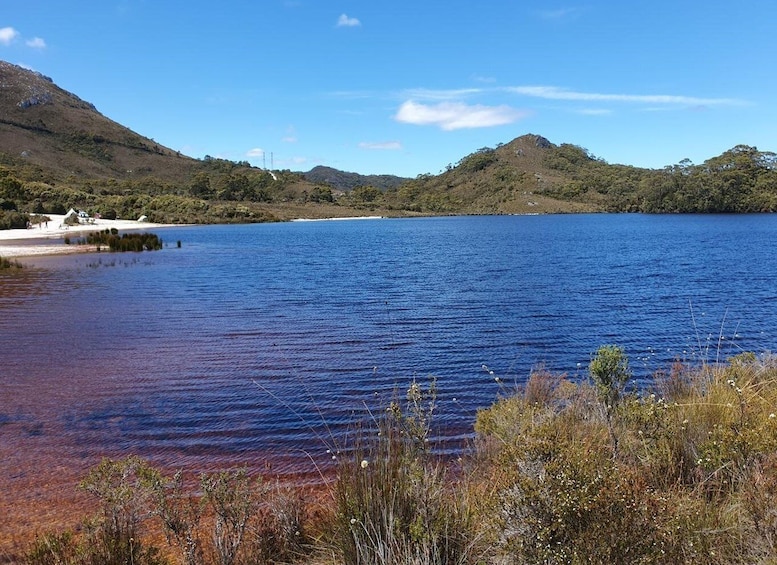 A lake surrounded by hills with a small beach and some buildings. 3