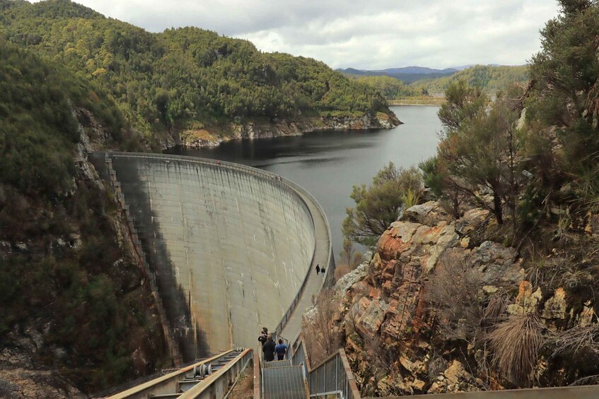 A large dam with people walking on the stairs leading up to it. 1