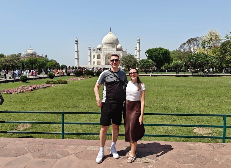 Una coppia in primo piano davanti al Taj Mahal, con una folla numerosa sullo sfondo. 4
