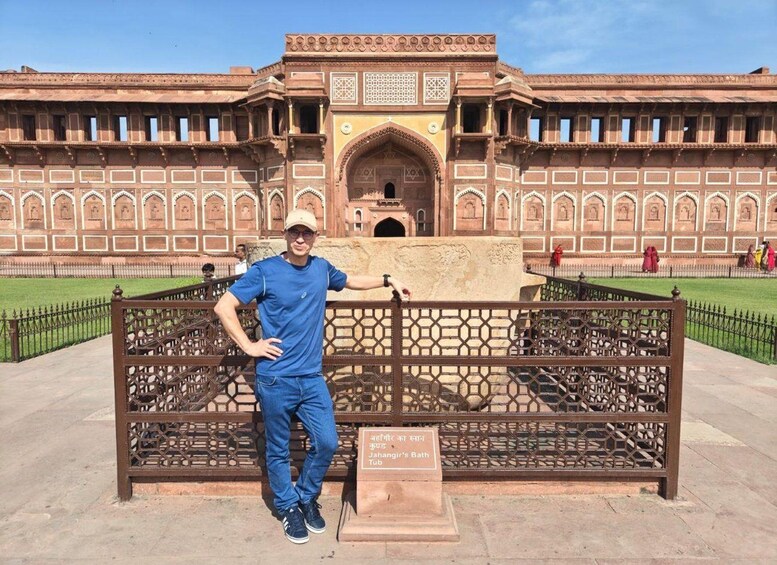 A man standing in front of a historical building with intricate architecture, including arches and detailed patterns. 5