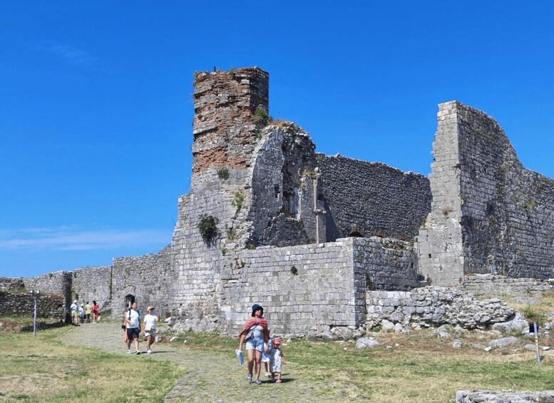 Ancient stone ruins with a tower, a pathway, and visitors. 3