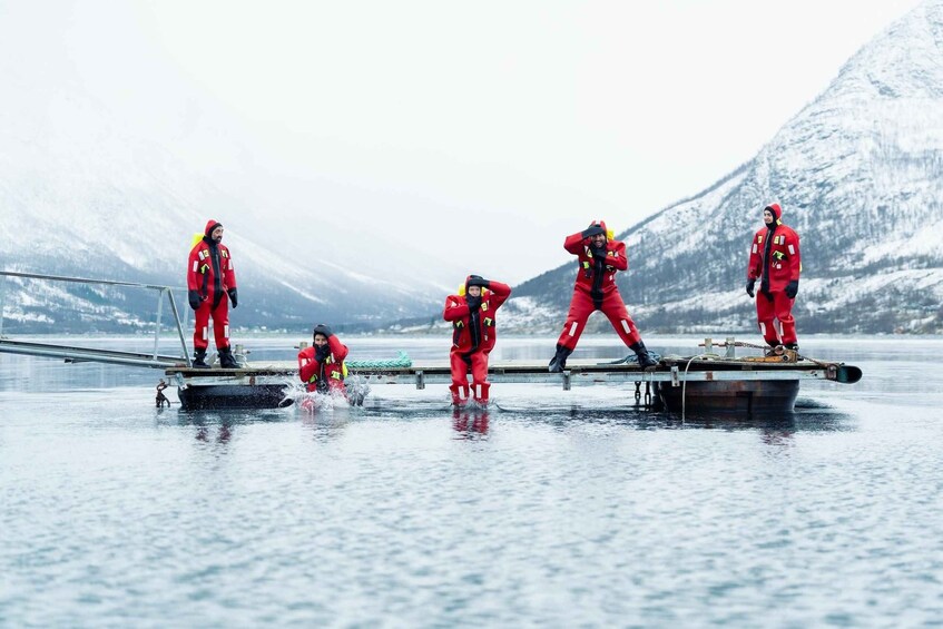 En gruppe mennesker i røde dragter på en frossen sø med bjerge i baggrunden. 2