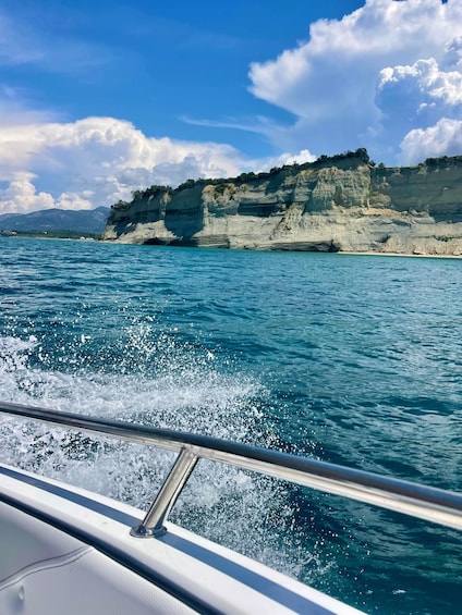 A boat moving through turquoise waters with white cliffs in the background. 5