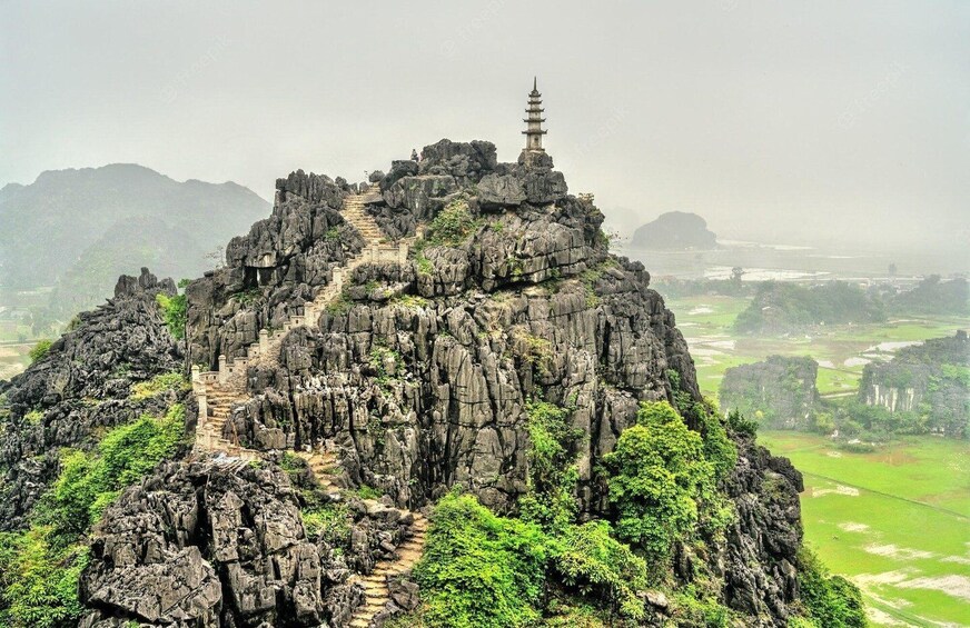 A temple on a rocky mountain peak with a staircase leading up to it. 1