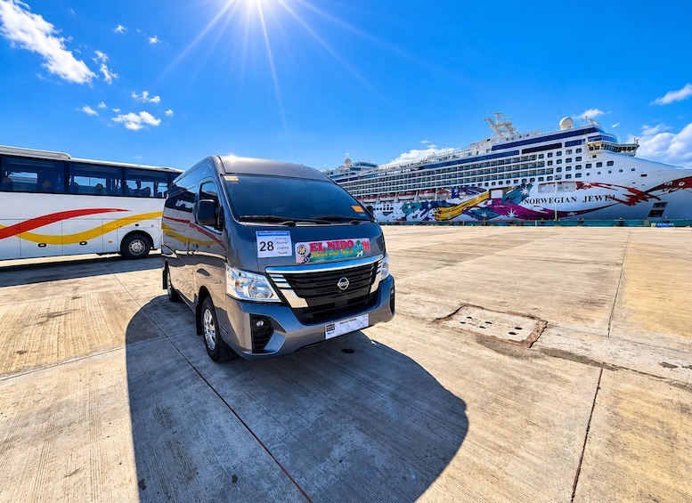 A bus parked in front of a cruise ship with a colorful design. 1