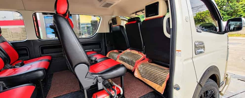 A vehicle interior with red and black seats, a central aisle, and a control panel on the right side. 2