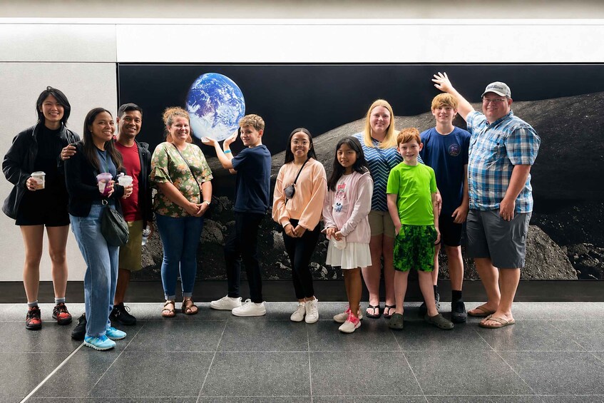 A group of people standing in front of a large display of the Earth. 5