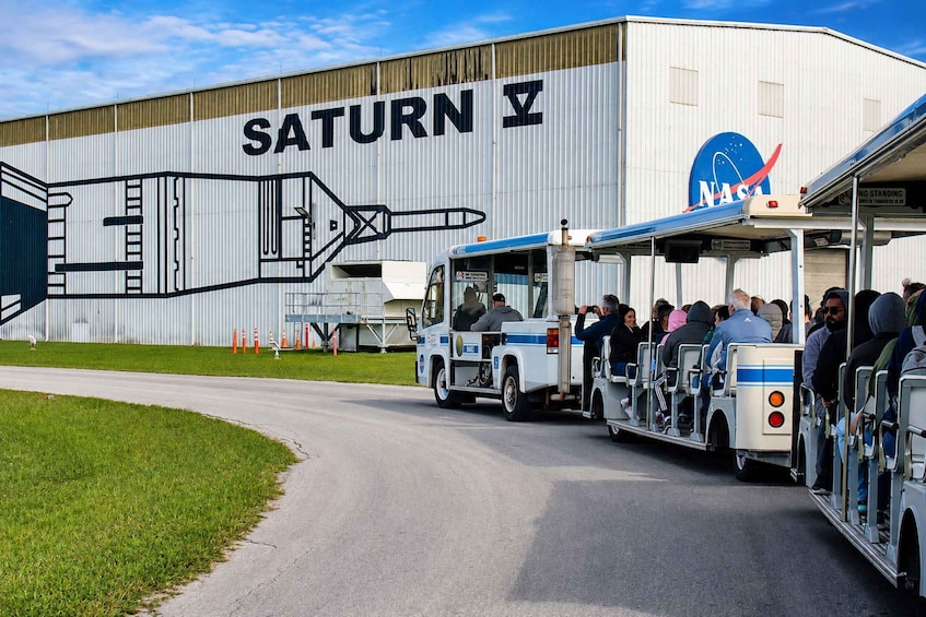 A Saturn V rocket model, a shuttle, and a NASA bus at a space center. 3