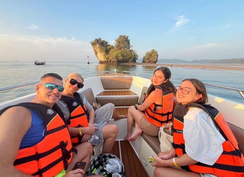 Un grupo de personas en un bote, con chalecos salvavidas, un mar tranquilo y una pequeña isla al fondo. 1