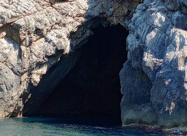A rocky cave entrance with clear water at the base. 5