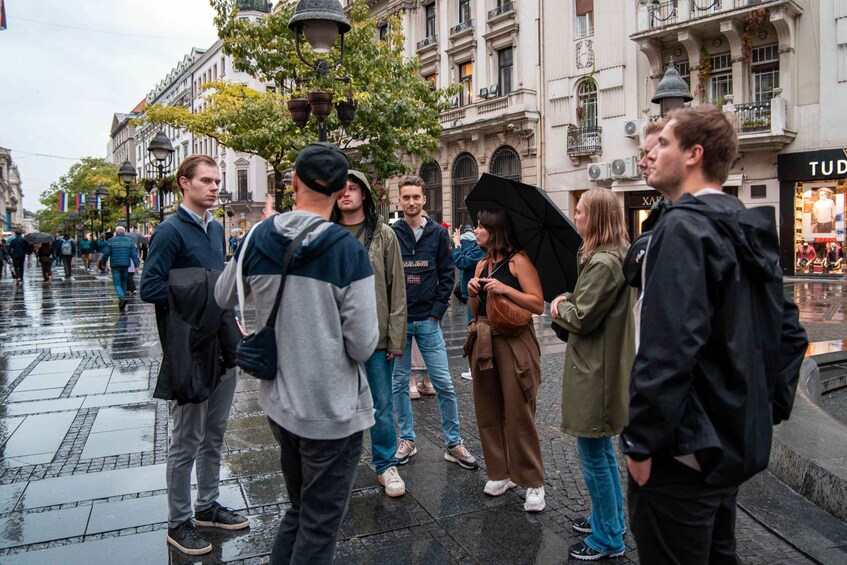 A group of people standing on a wet city street with historic buildings in the background. 3