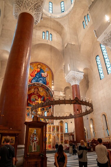 A church interior with large columns, stained glass windows, and religious paintings. 4