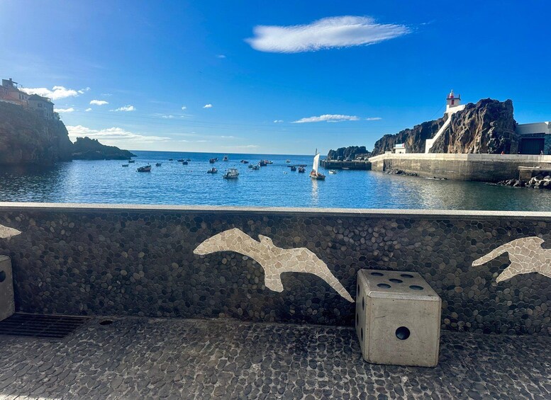 A coastal scene with boats, a lighthouse, and a rocky cliff. 4