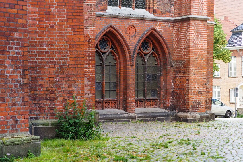 A red brick church with two large arched windows and a stone cross above the entrance. 2
