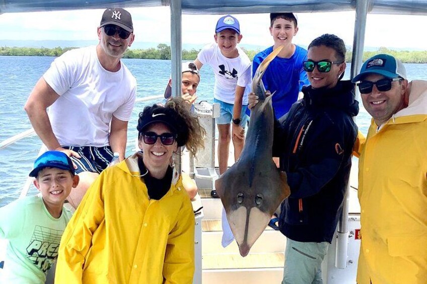 A group of people on a boat holding a stingray. 1