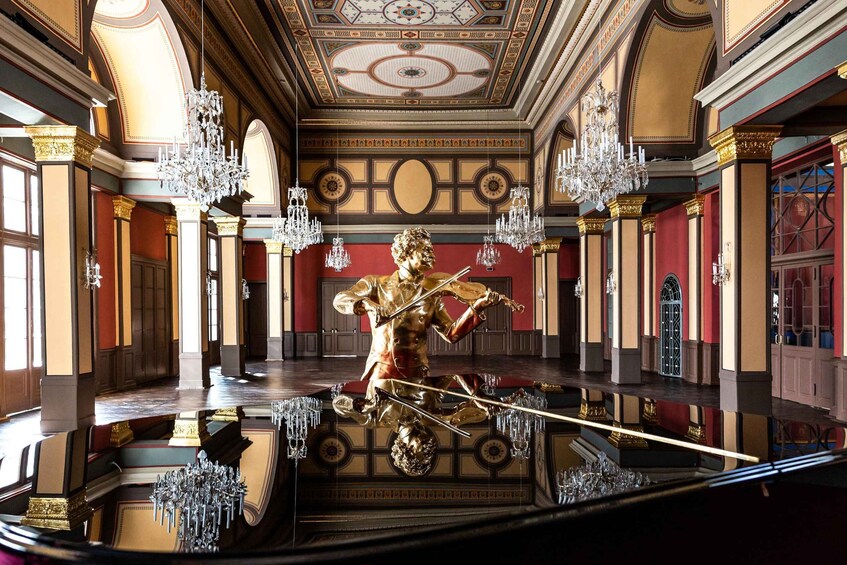 A grand hall with ornate chandeliers, a golden statue, and a reflective floor. 1