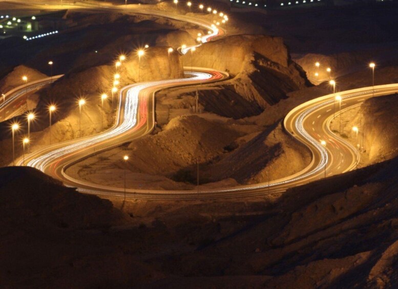 A winding road at night with light trails from vehicles. 2