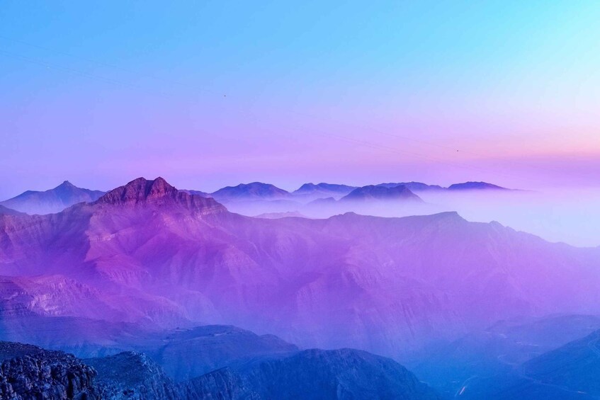 A mountain range with a purple and blue sky. 1