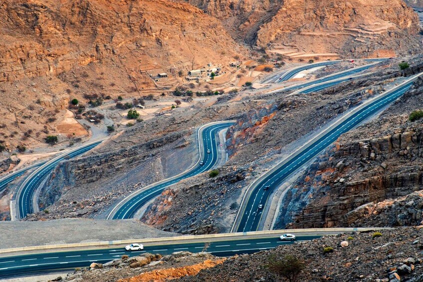 A winding mountain road with multiple lanes, surrounded by rocky terrain and sparse vegetation. 5