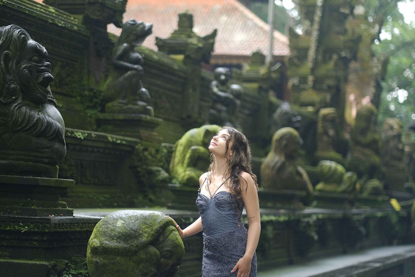 Una persona in abito si trova in un cortile di un tempio, con intagli in pietra e statue. 3