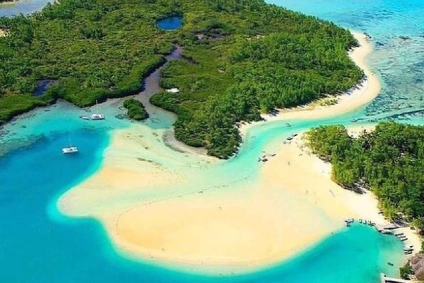 An aerial view of a tropical island with a sandy beach, clear turquoise waters, and dense green vegetation. 1