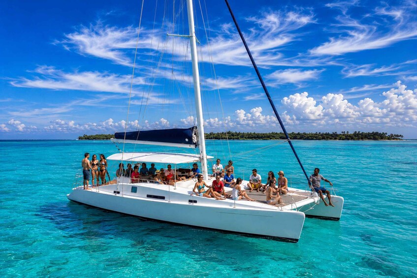 A sailboat with people on board, surrounded by clear turquoise water and a distant island. 5