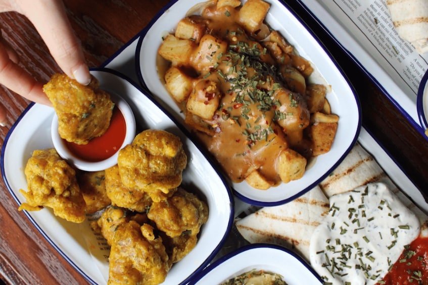 A variety of dishes including a bowl of potato chunks in sauce, a bowl of breaded items, and a small bowl of dipping sauce. 4