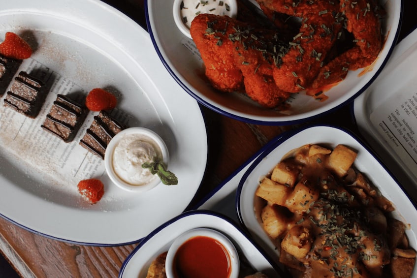 A variety of dishes including a plate with chocolate pieces and strawberries, a bowl of red sauce, and a dish with potatoes and herbs. 3