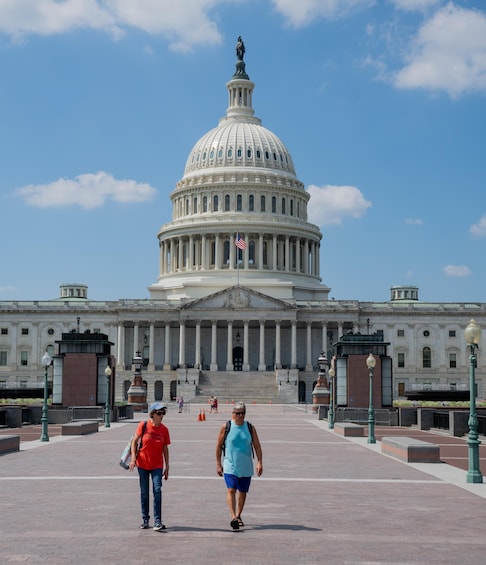 The United States Capitol building with two people walking in front. 3
