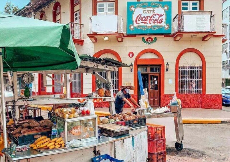 A street vendor preparing food at a roadside stall with a green canopy. 1