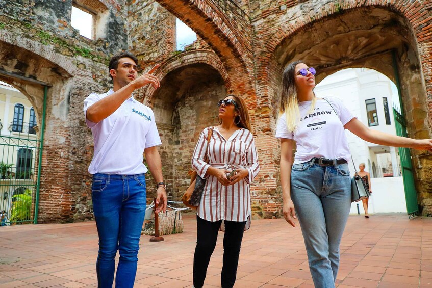 Three people walking in an old building with brick arches. 2