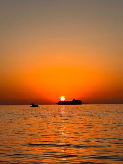 Un atardecer sobre el océano con un barco y una embarcación más pequeña a lo lejos. 5