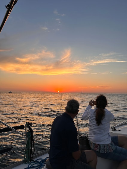 Una pareja en un bote durante el atardecer, con el sol poniéndose sobre el océano. 3