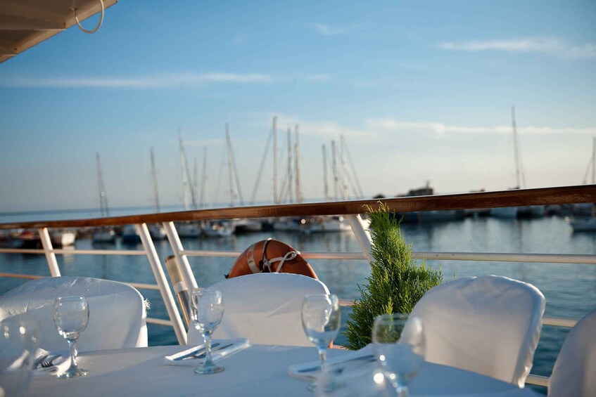 A table set for dining with a view of boats at a marina. 5