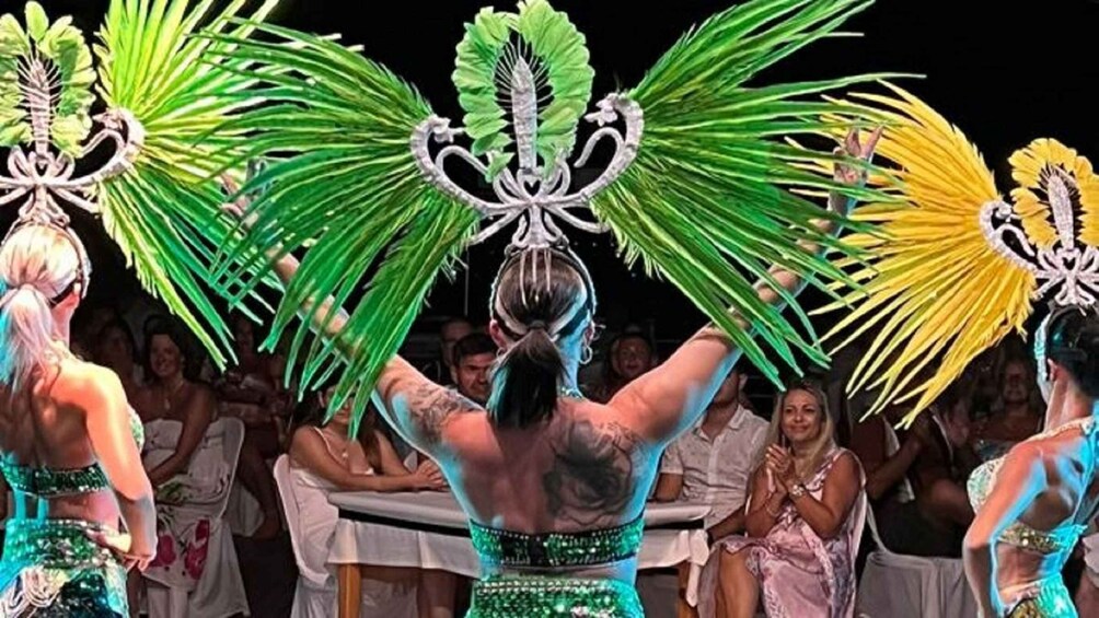 A person with a tattoo on their back, wearing a green and silver outfit with a decorative headpiece. 4