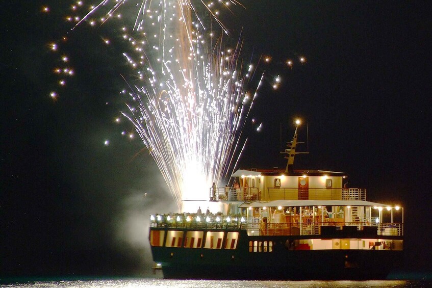 A boat with lights and fireworks in the background. 1