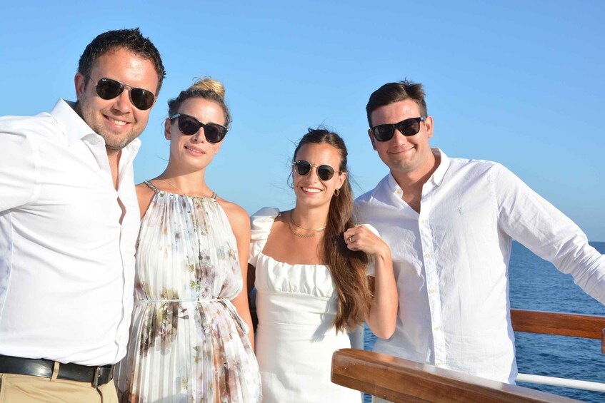 A group of people on a boat with a clear blue sky and ocean in the background. 3