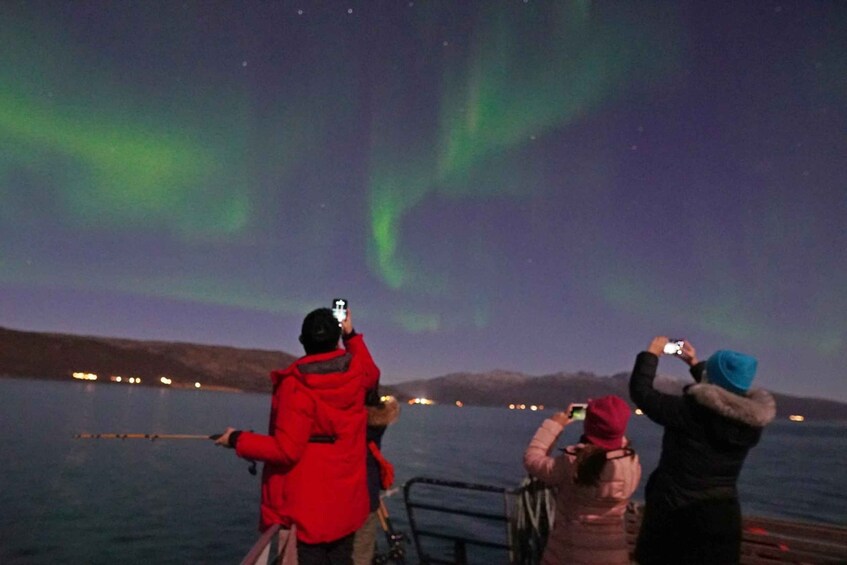 Personas observando las auroras boreales sobre un cuerpo de agua. 2