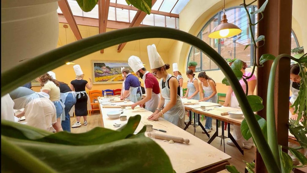 Un grupo de personas en una cocina, con gorros de chef y delantales, cocinando. 4