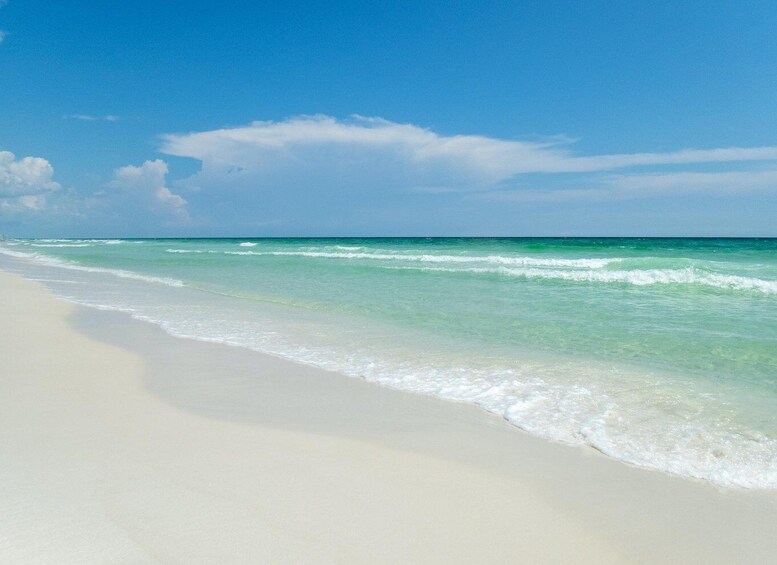 A beach with clear turquoise water and white sand under a blue sky. 4