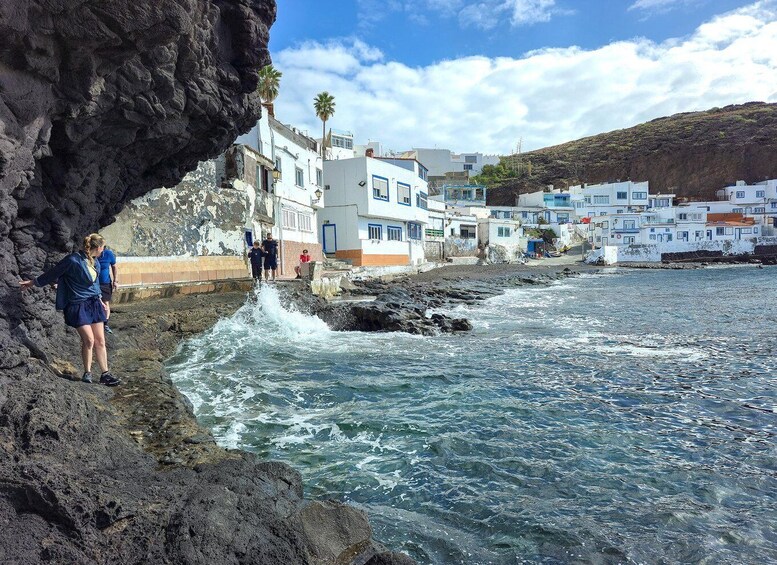 A coastal town with white buildings, a rocky cliff, and waves crashing against the shore. 4