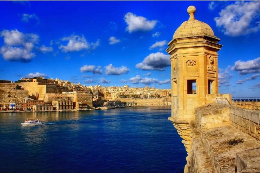 A coastal cityscape with a prominent tower, a body of water, and a historic fortification. 5