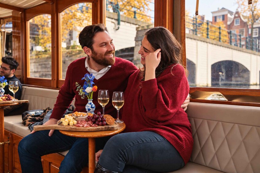 Un couple est assis à une table, devant une sélection de fromages, des raisins et des verres de vin. 5