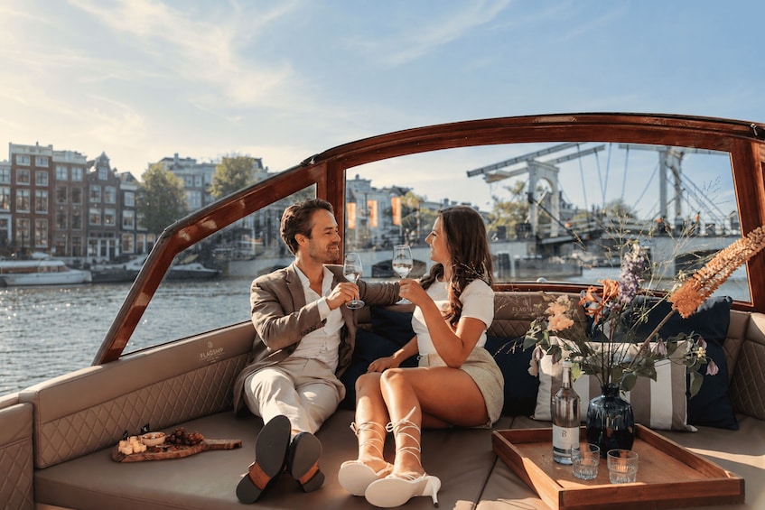 A couple on a boat with a cityscape and bridge in the background. 2